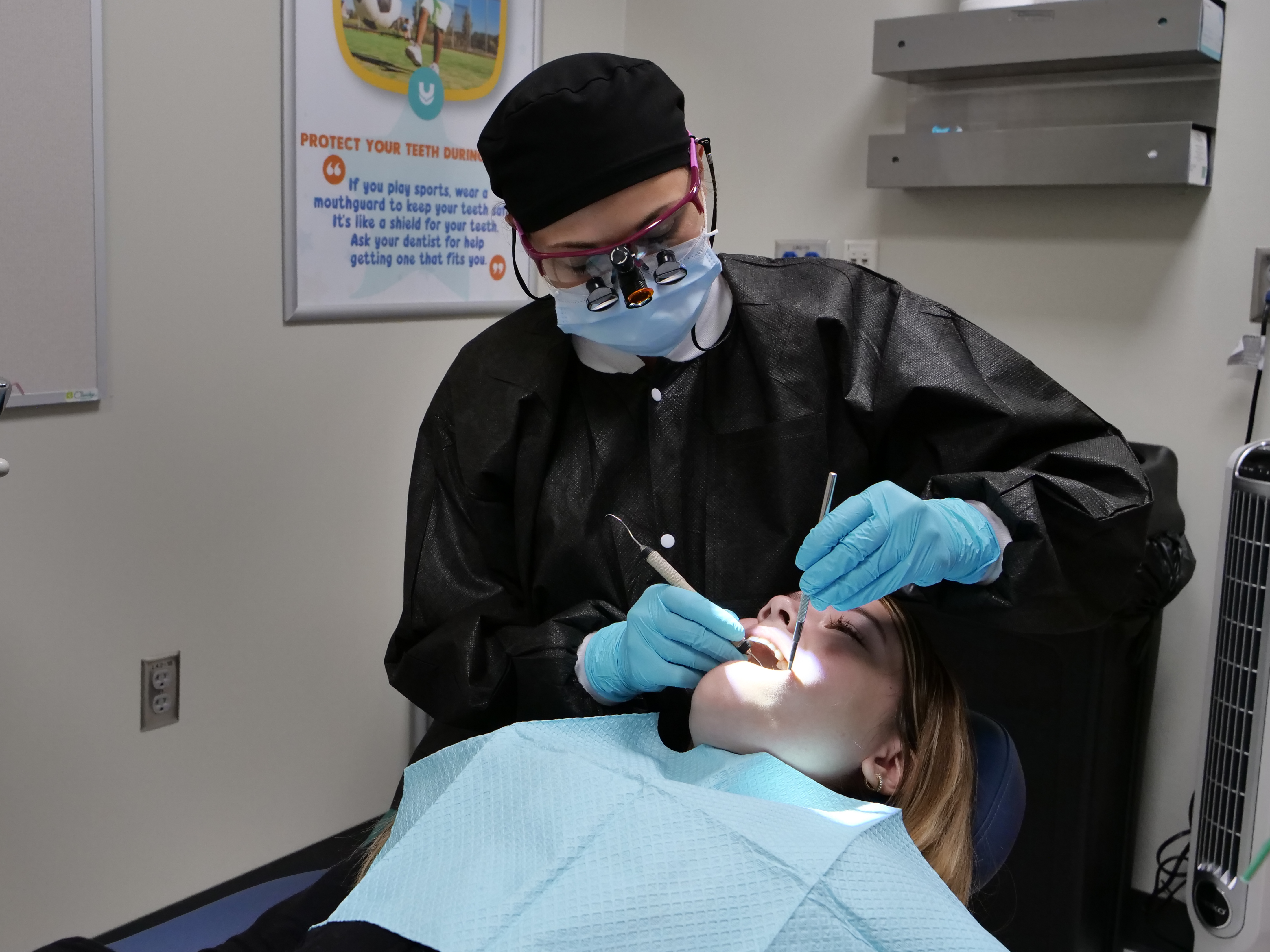 dentist cleaning a child's teeth with a dental pick